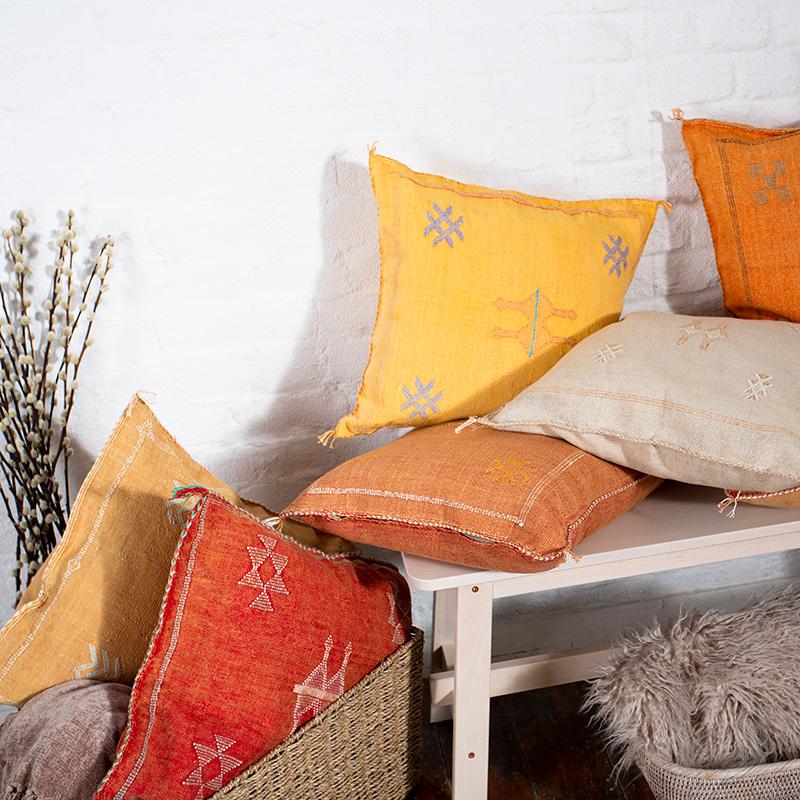  Orange and red scatter cushions on a bench and in a basket.